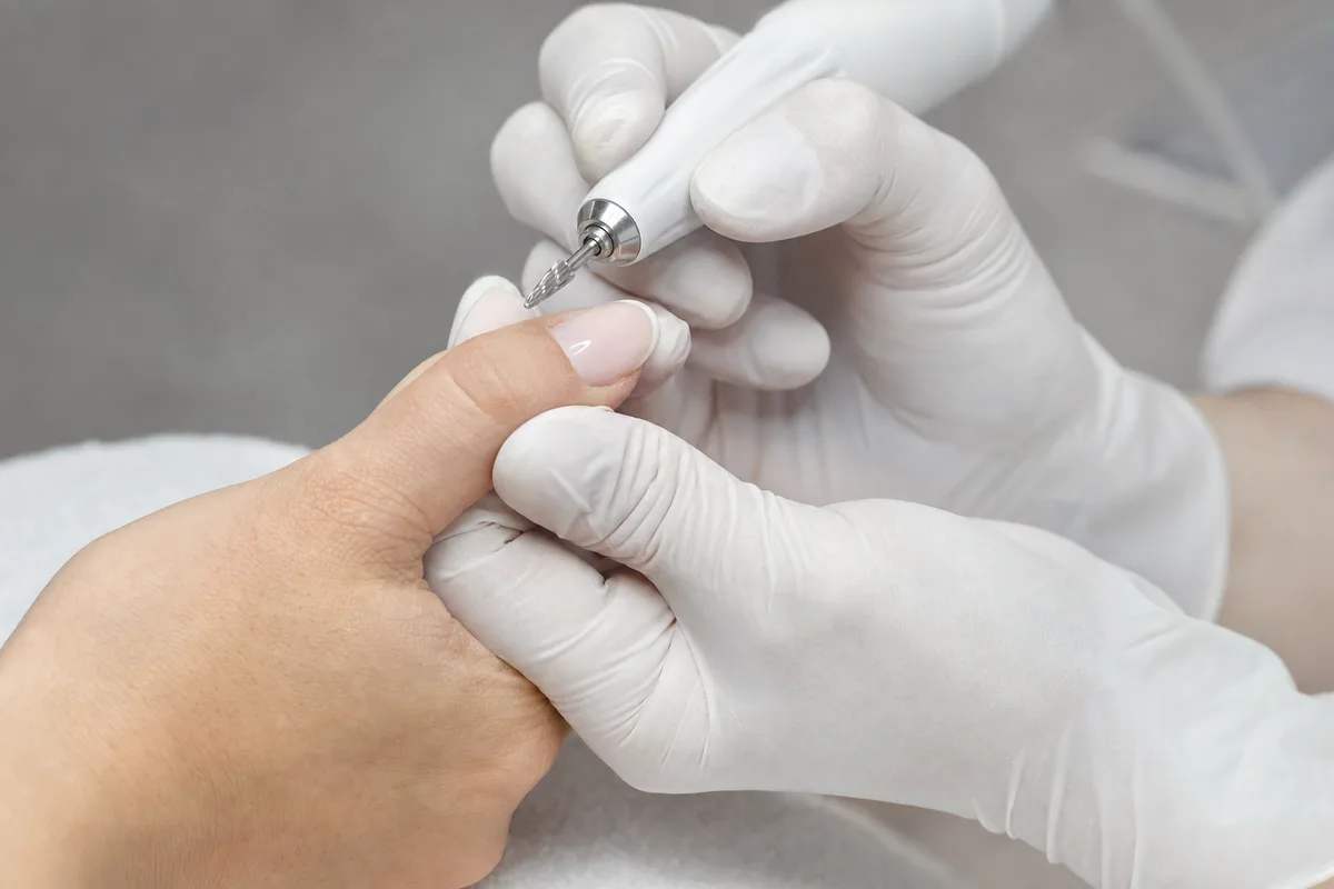 Mains posées sur une serviette blanche pendant un soin des ongles en institut